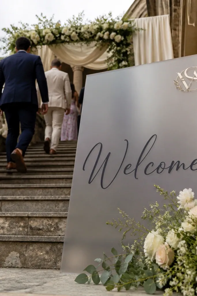 Frosted acrylic sign with large Welcome script and a small monogram in one corner