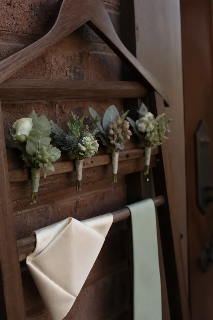 Boutonniere pin on a wooden hanger with a folded tie and card
