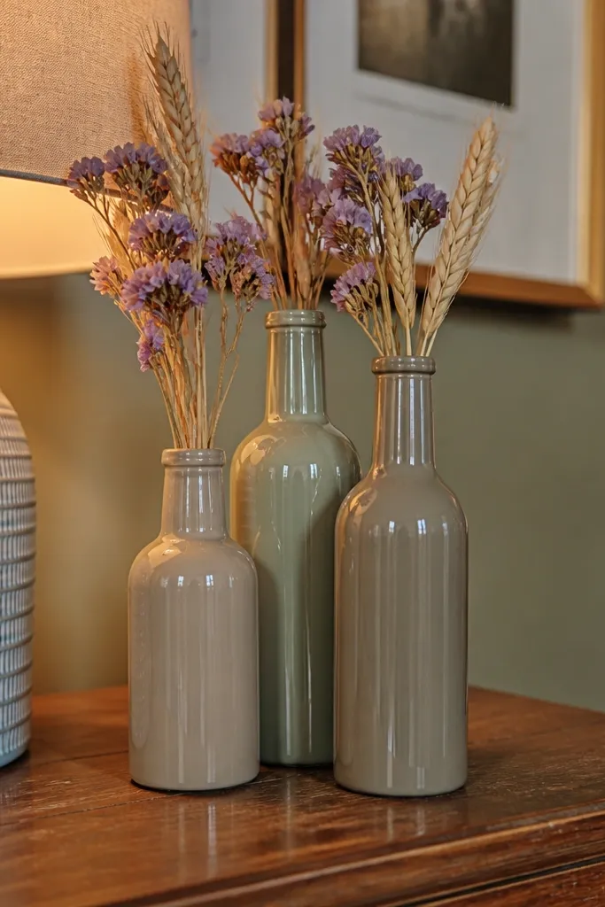 Cluster of muted painted glass bottles in sage and clay shades on a table