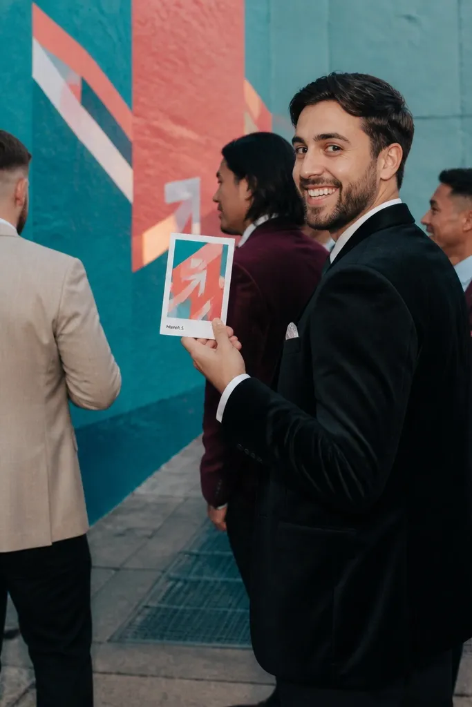 Men walking together in front of a colorful mural holding numbered clue cards
