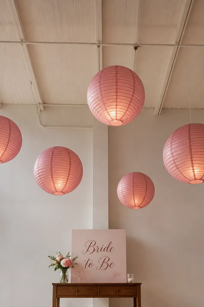 Cream paper lanterns hanging in a straight line with one blush sign below