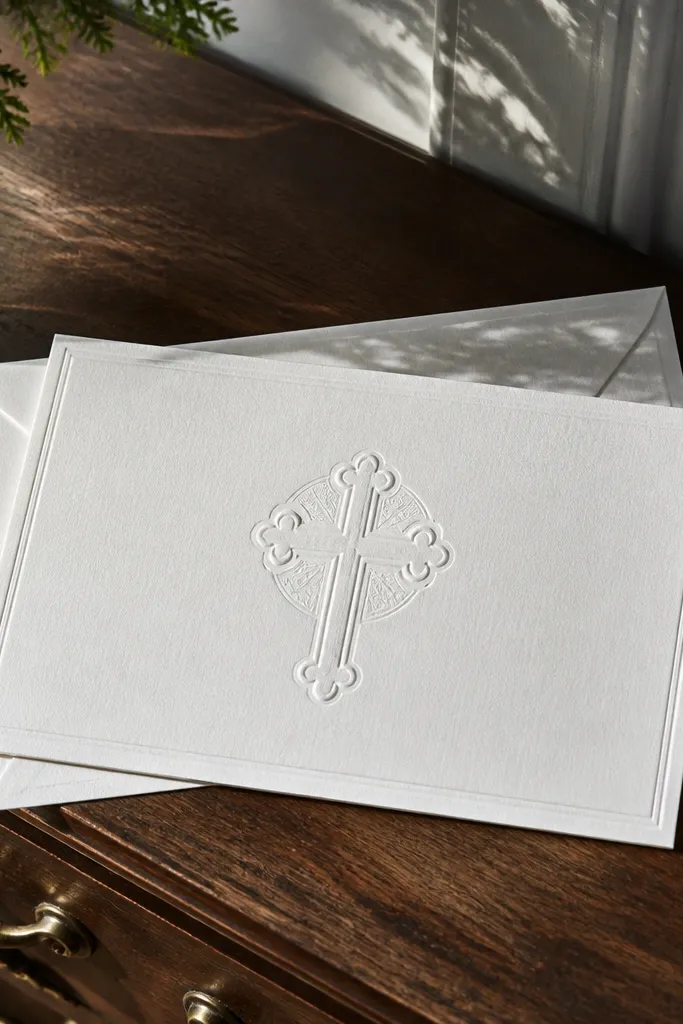 White invitation with embossed cross seal and crisp black typography