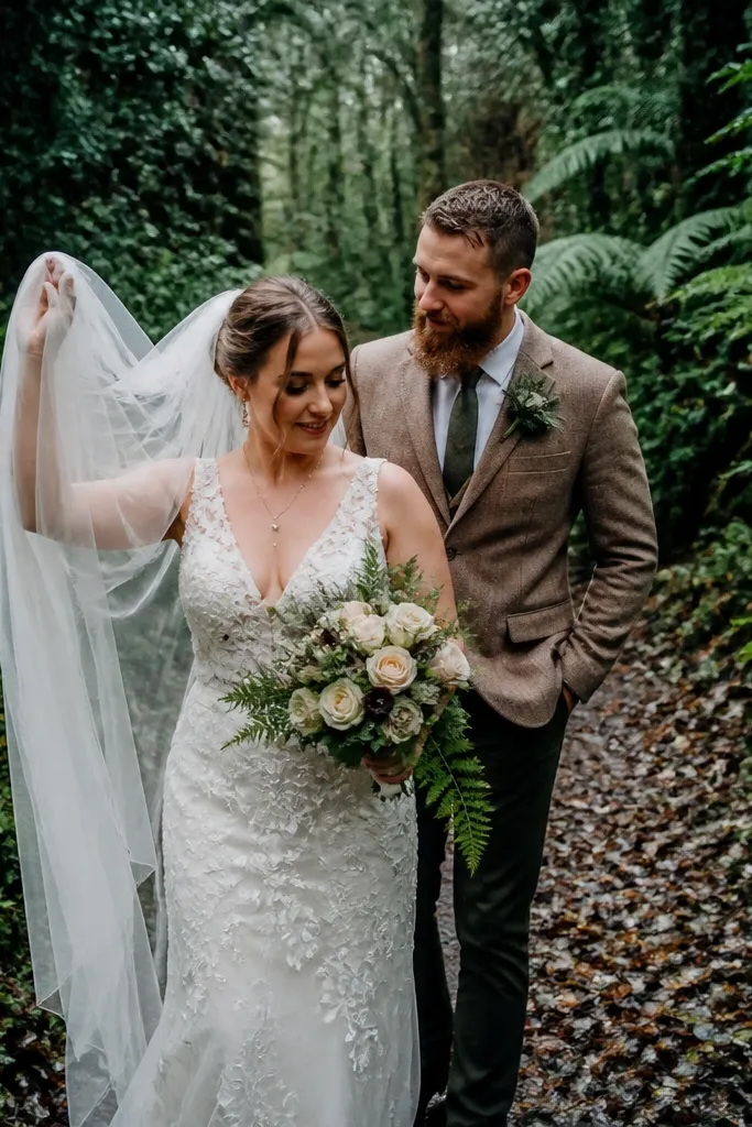 Couple walking through a green forest with a lifted veil