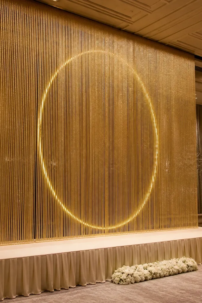 Gold fringe curtain with a soft circular halo light centered on a wedding stage