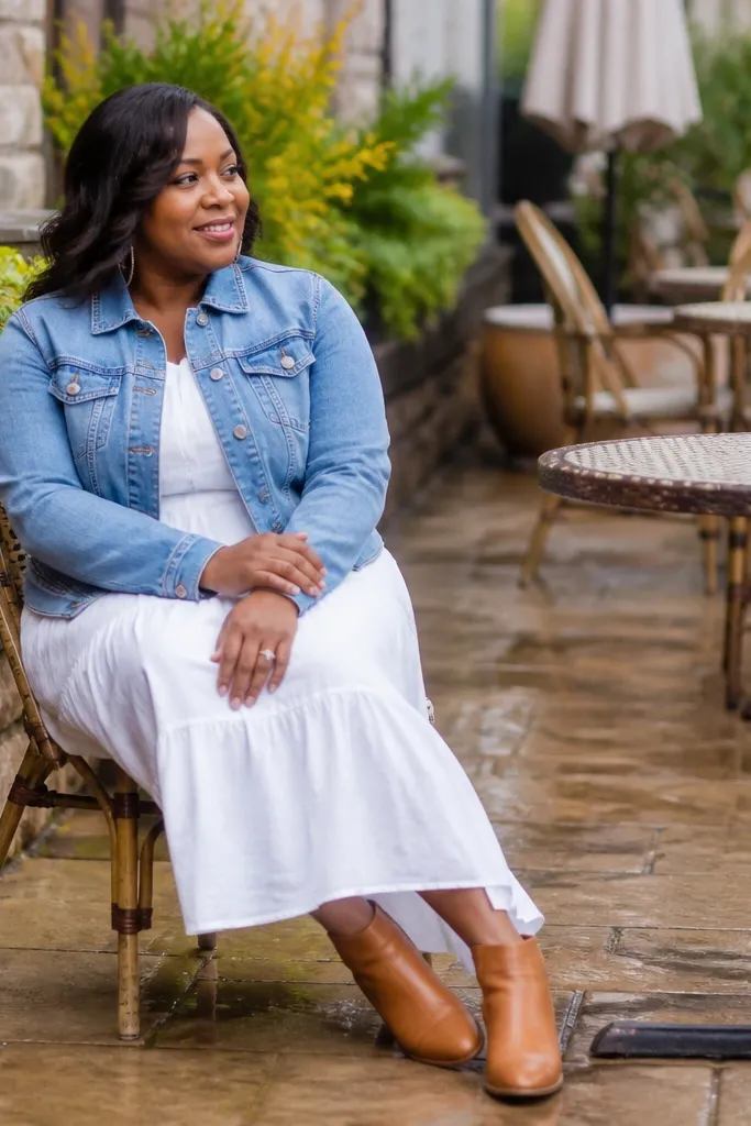 Light blue denim jacket worn over a white midi dress with tan ankle boots