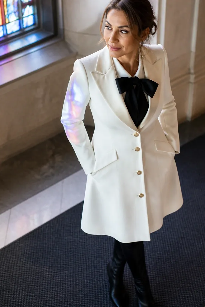 Cream tuxedo-style dress with black satin bow detail and black ankle boots