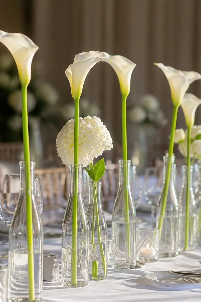 Slim glass bottles with one white flower each lined on a reception table