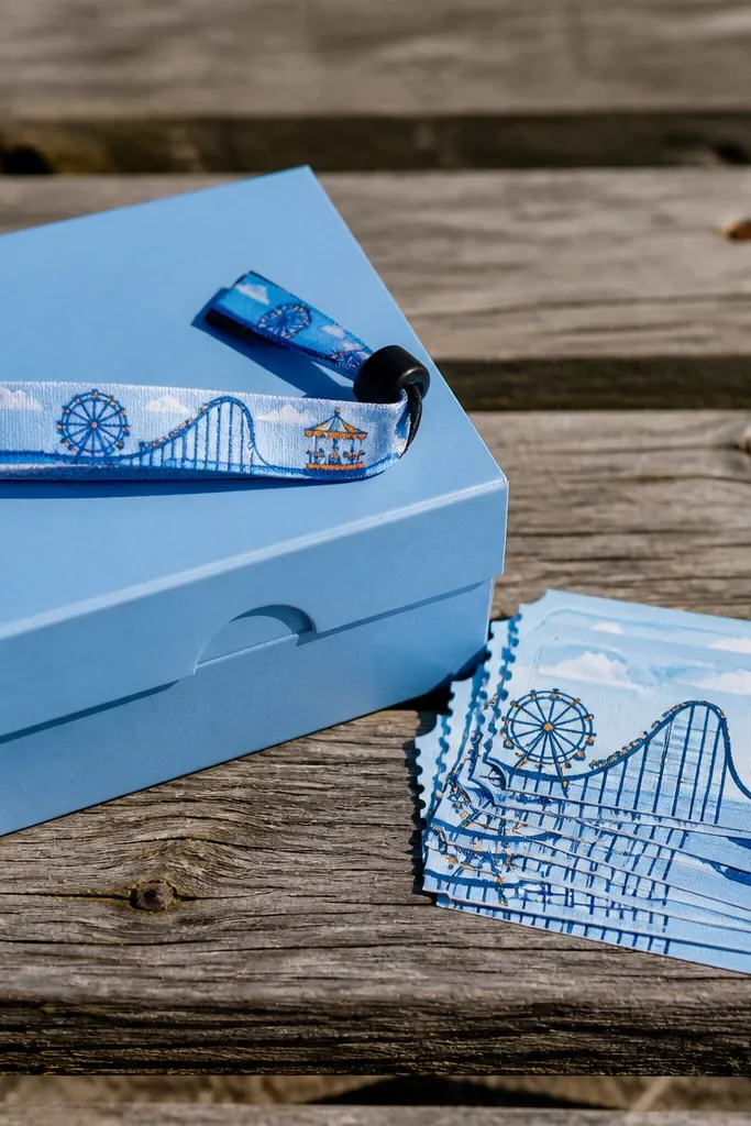 Sky blue box with faux ticket stub cards and a small striped wristband