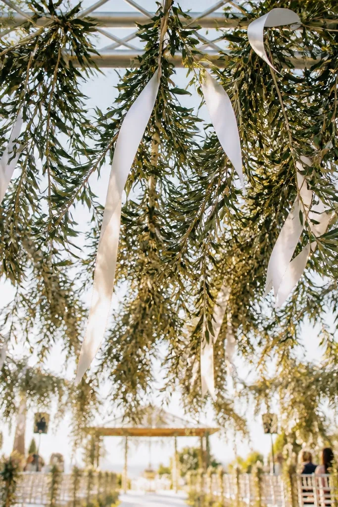Olive branch garland with white ribbon cascades hanging from a stage truss