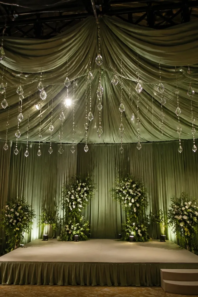 Sage draped canopy above a stage with hanging crystal drops