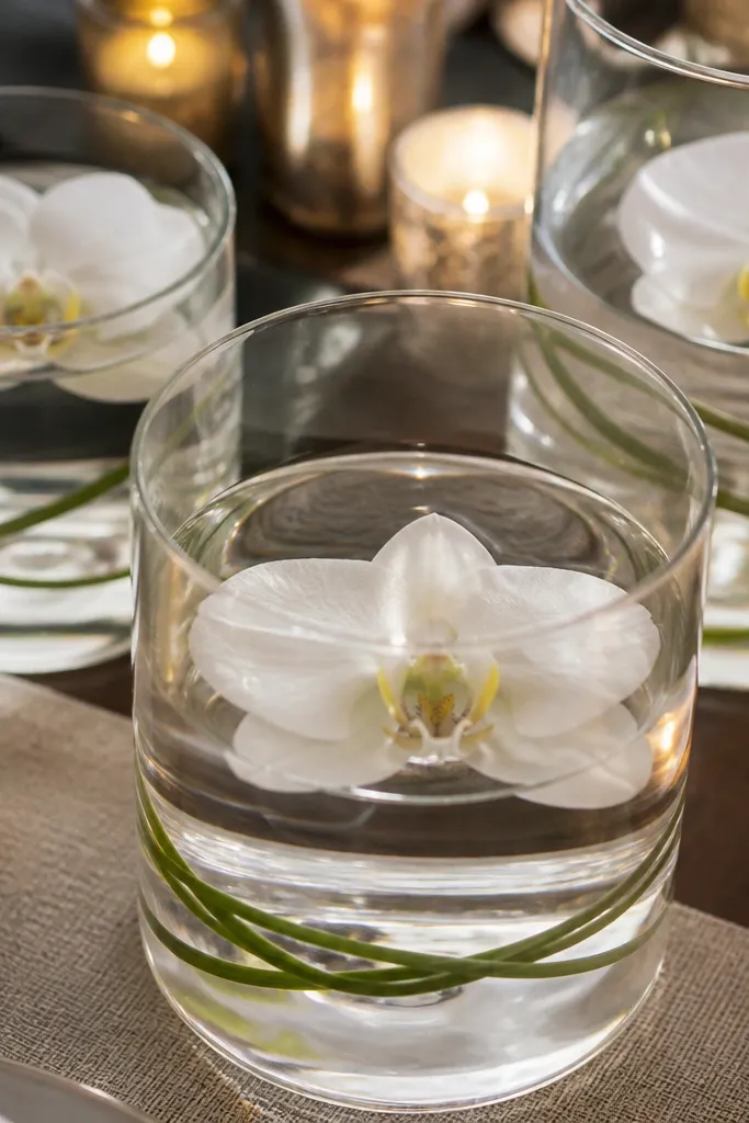 Clear cylinder vases with water and white orchid blooms floating