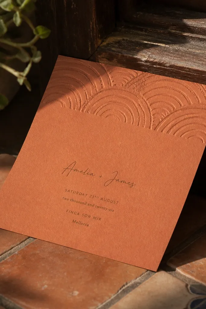 Terracotta invitation with stamped crescent lines across the top