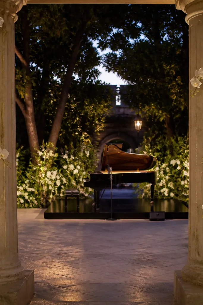 Two light stone columns with trailing orchid vines framing the stage