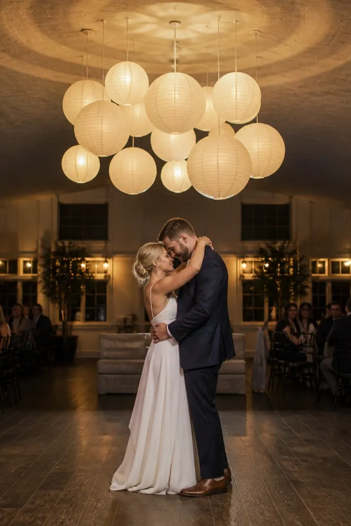 Hanging white paper lantern cluster above stage with subtle greenery garland