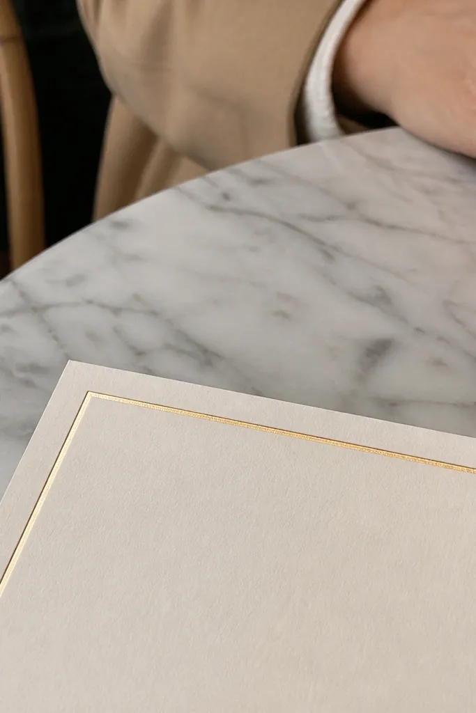 Cream card with two thin gold lines and a wider blank center