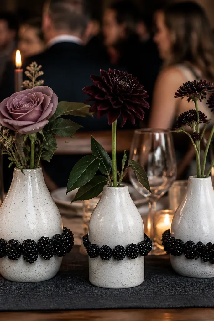 White stoneware bud vases with dark berry stems as accents on a wedding table