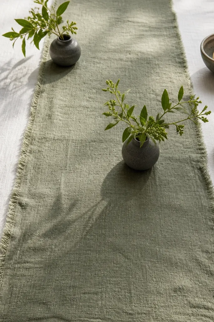 Cream linen runner on a table with dark candles and brass accents