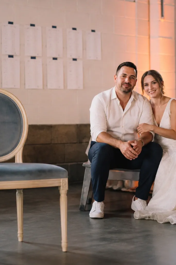 Couple seated near a seating chart sign with one decorative chair in frame
