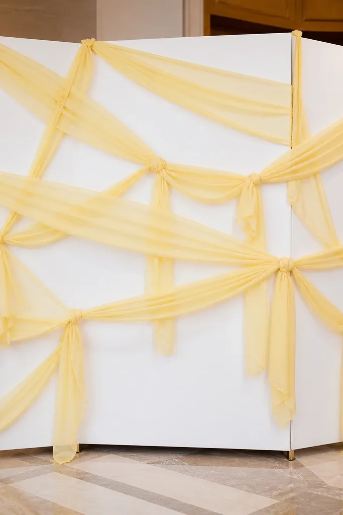 White backdrop with butter yellow ribbon streamers and small sign squares