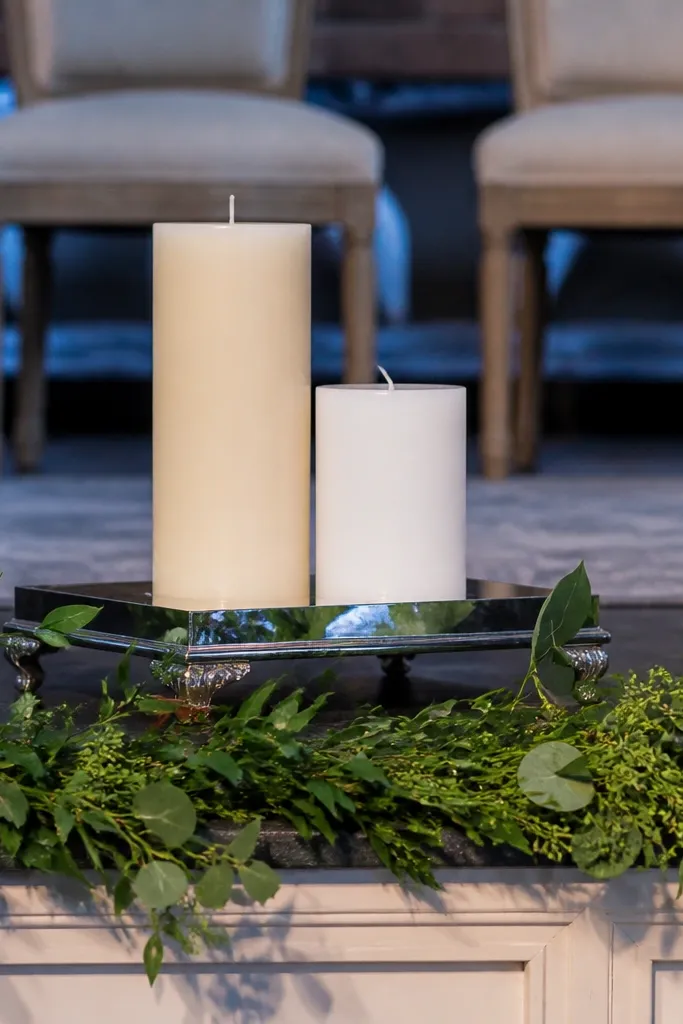 Two white candles on a small mirrored tray at the stage center