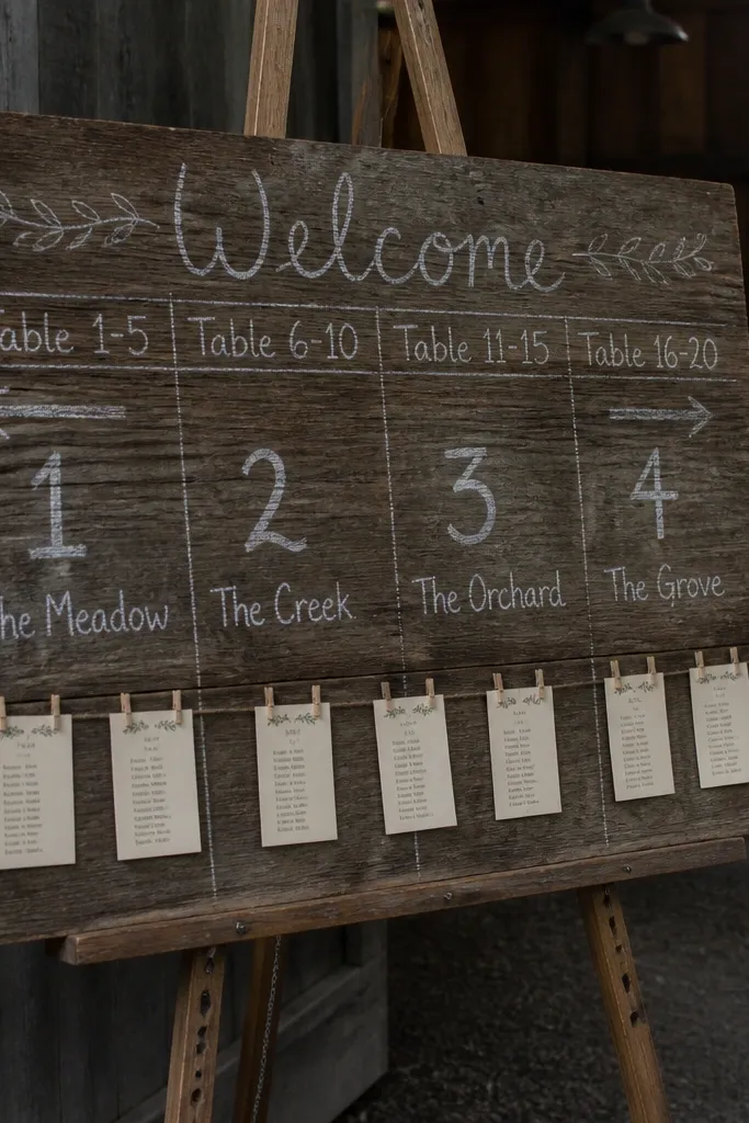 Wood seating chart board with chalk lettering and small pinned table cards