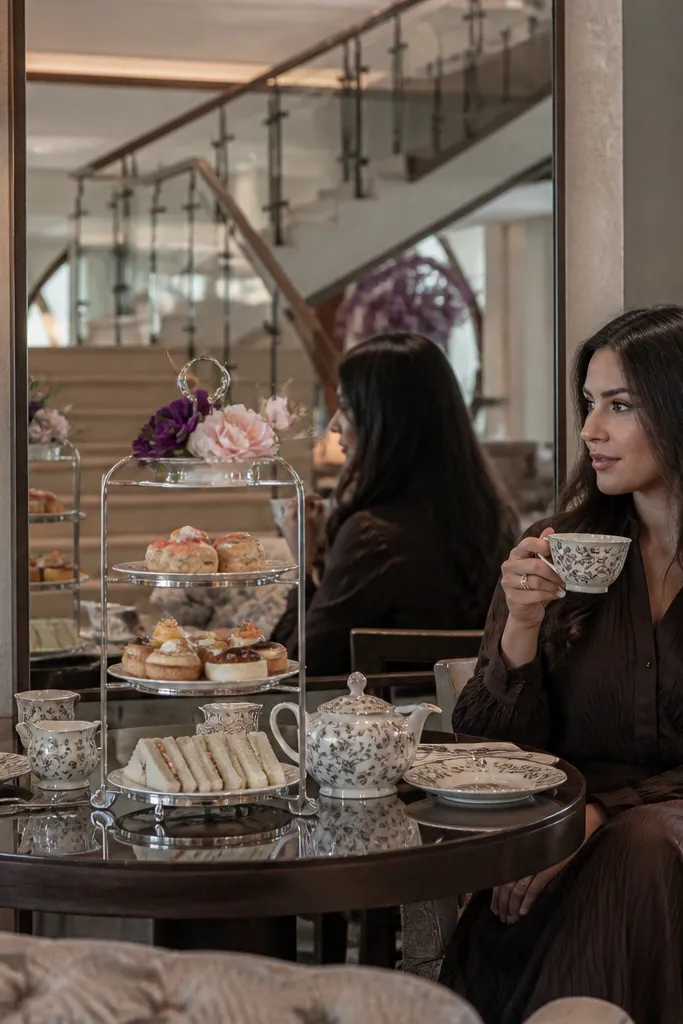 Hotel lobby table near a mirror with small florals, bride sign, and afternoon tea tray