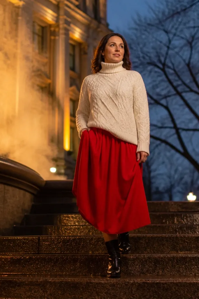 Cream cable turtleneck with a red midi skirt and black riding boots